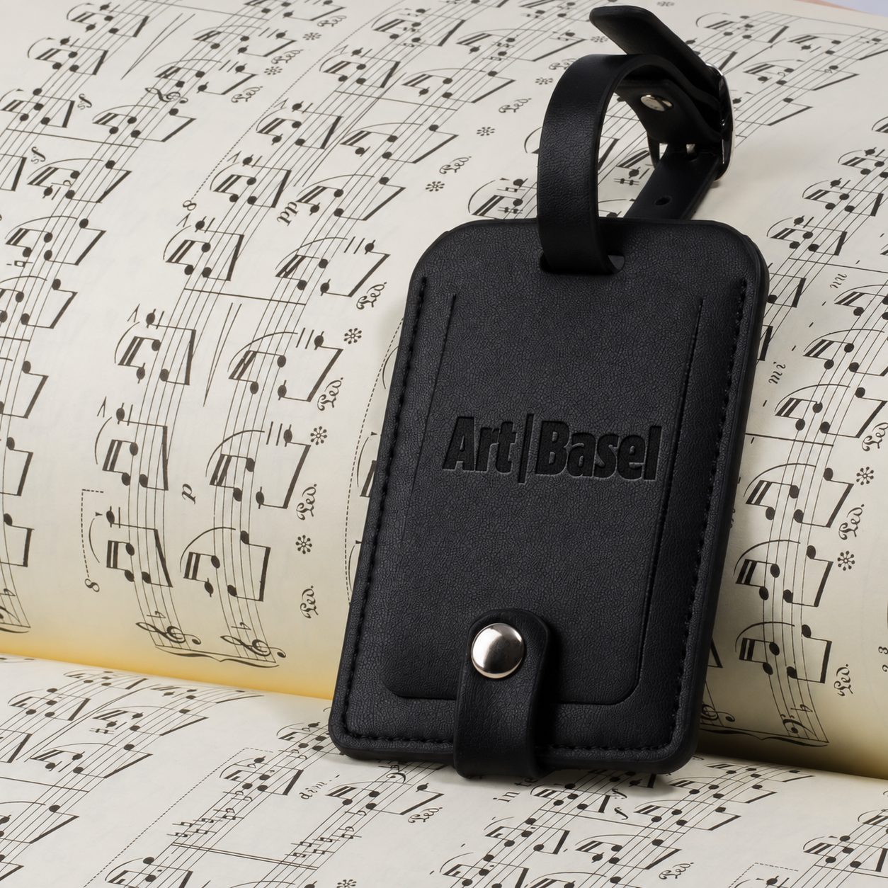 Black leather luggage tag blind debossed with the Art Basel logo