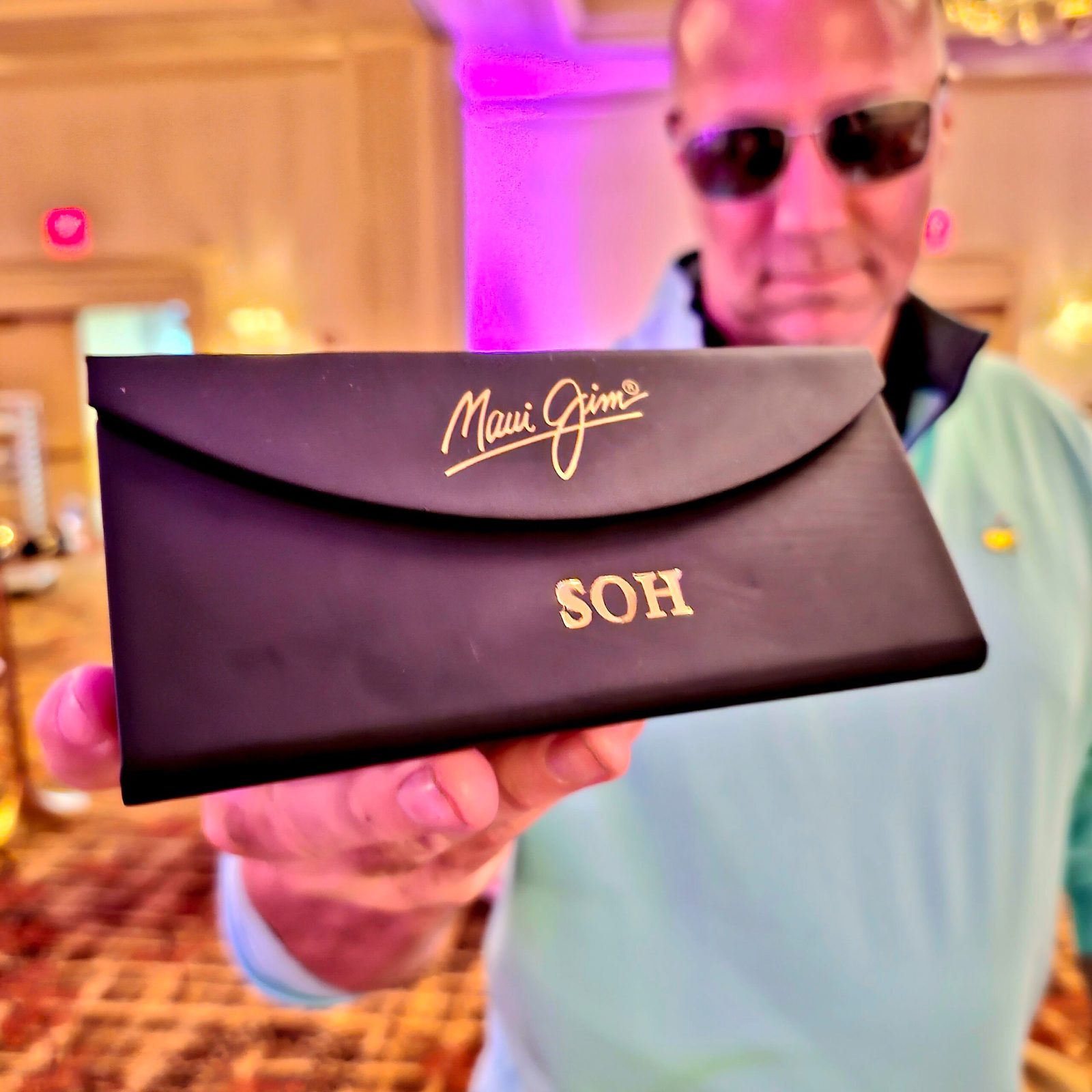 A guest holding a black sunglasses case foil stamped with his initials in gold