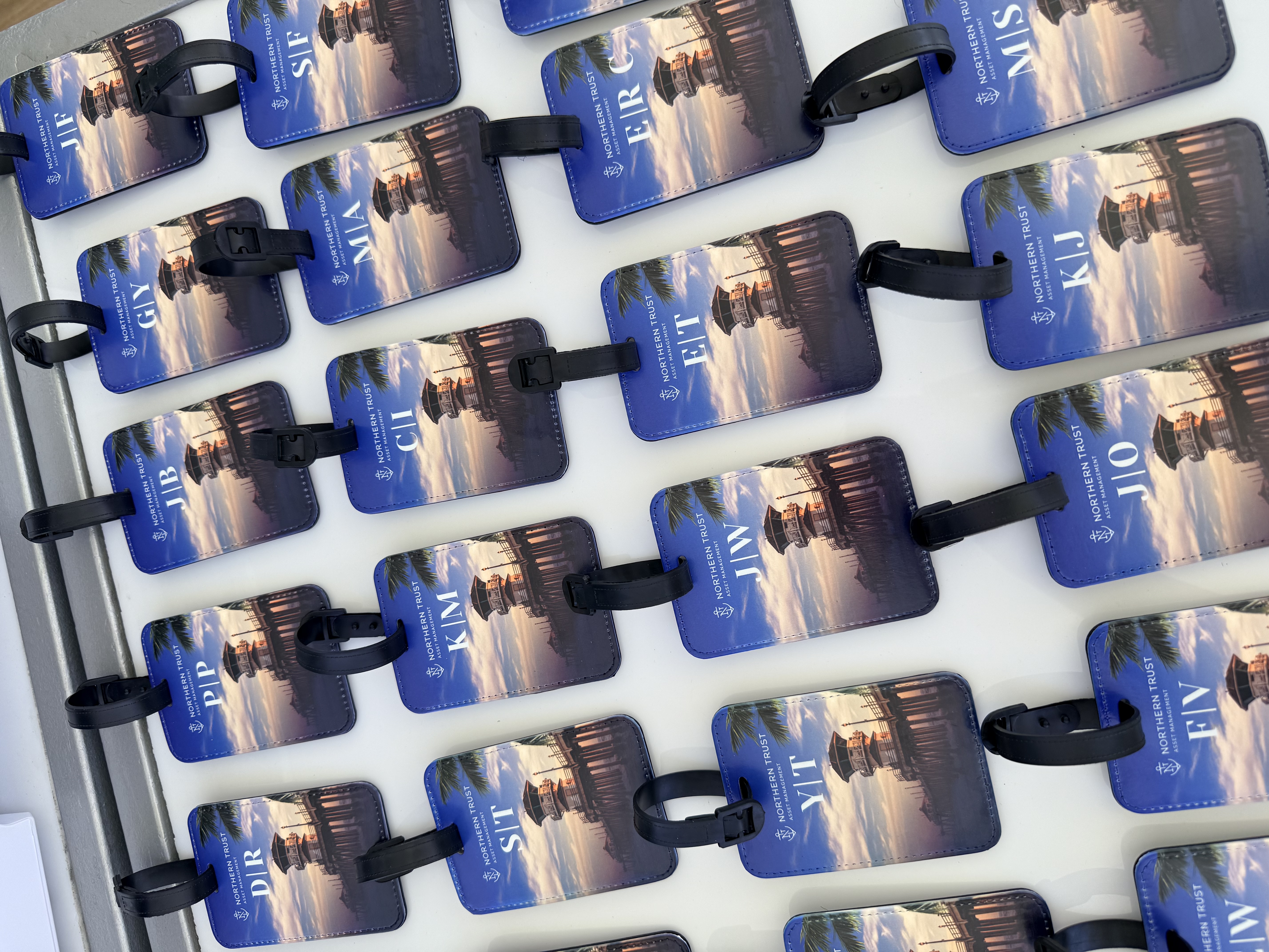 Rows of special edition Northern Trust luggage tags, each personalized with a guest monogram over a Huntington Beach Pier sunset