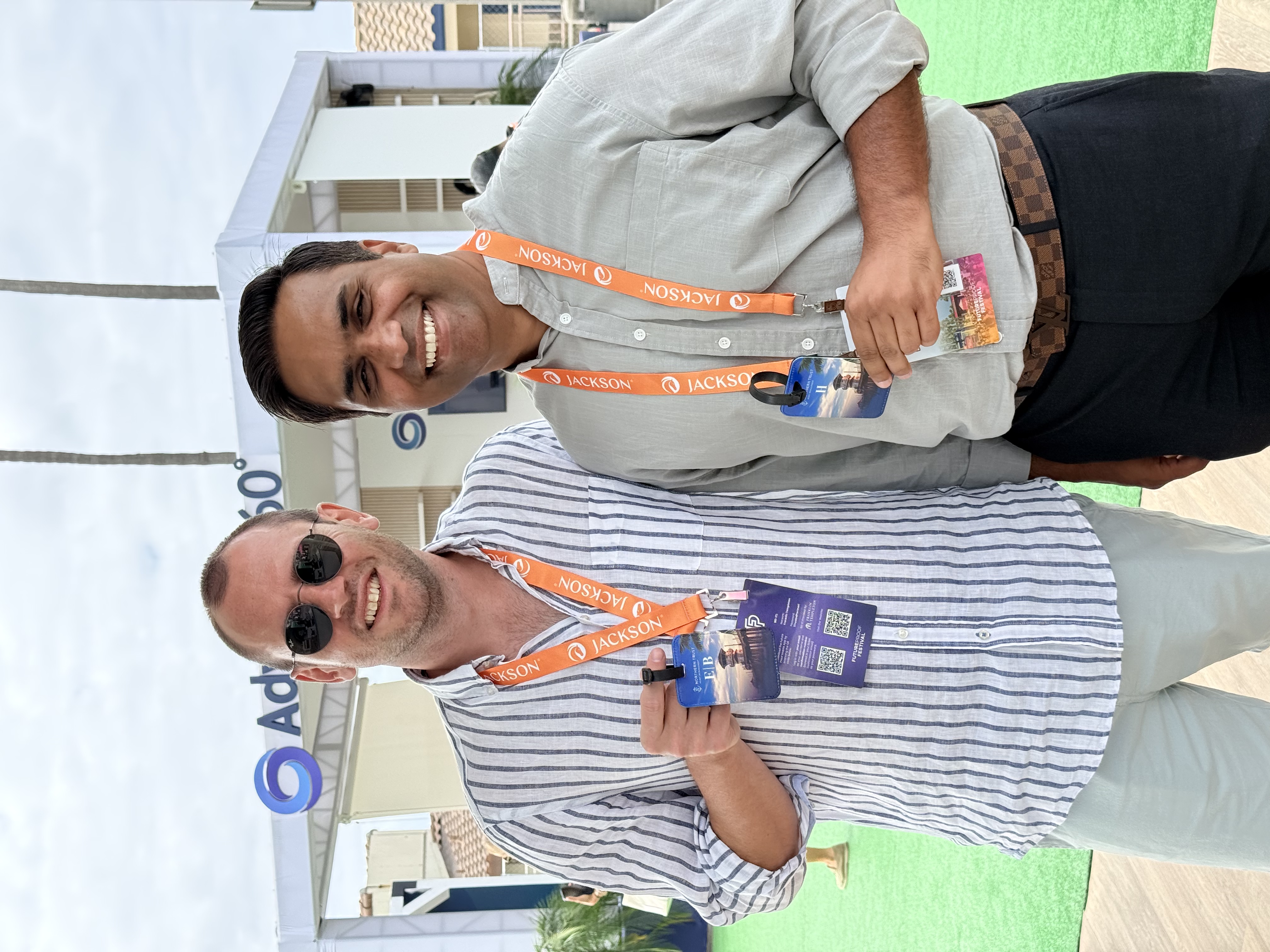 Two Future Proof attendees holding their monogrammed Northern Trust luggage tags on the festival green